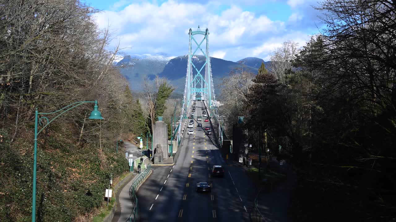 여름날 록키산맥을 달리는 구름과 함께 밴쿠버의 스탠리 공원을 향해 라이온스 게이트 다리를 건너 운전하는 자동차의 시간경과