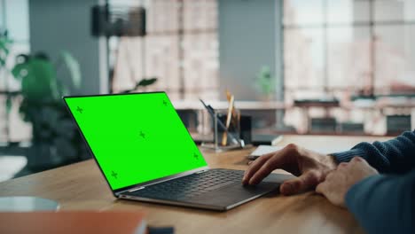 cerca de las manos de un especialista caucásico trabajando en una computadora portátil con pantalla verde simulacro de pantalla en la sala de estar de casa. hombre independiente hablando con clientes a través de internet en redes sociales.