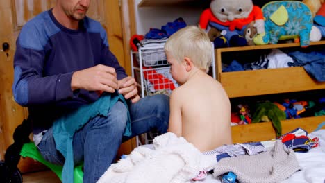 padre vistiendo a su hijo en el dormitorio en casa 4k