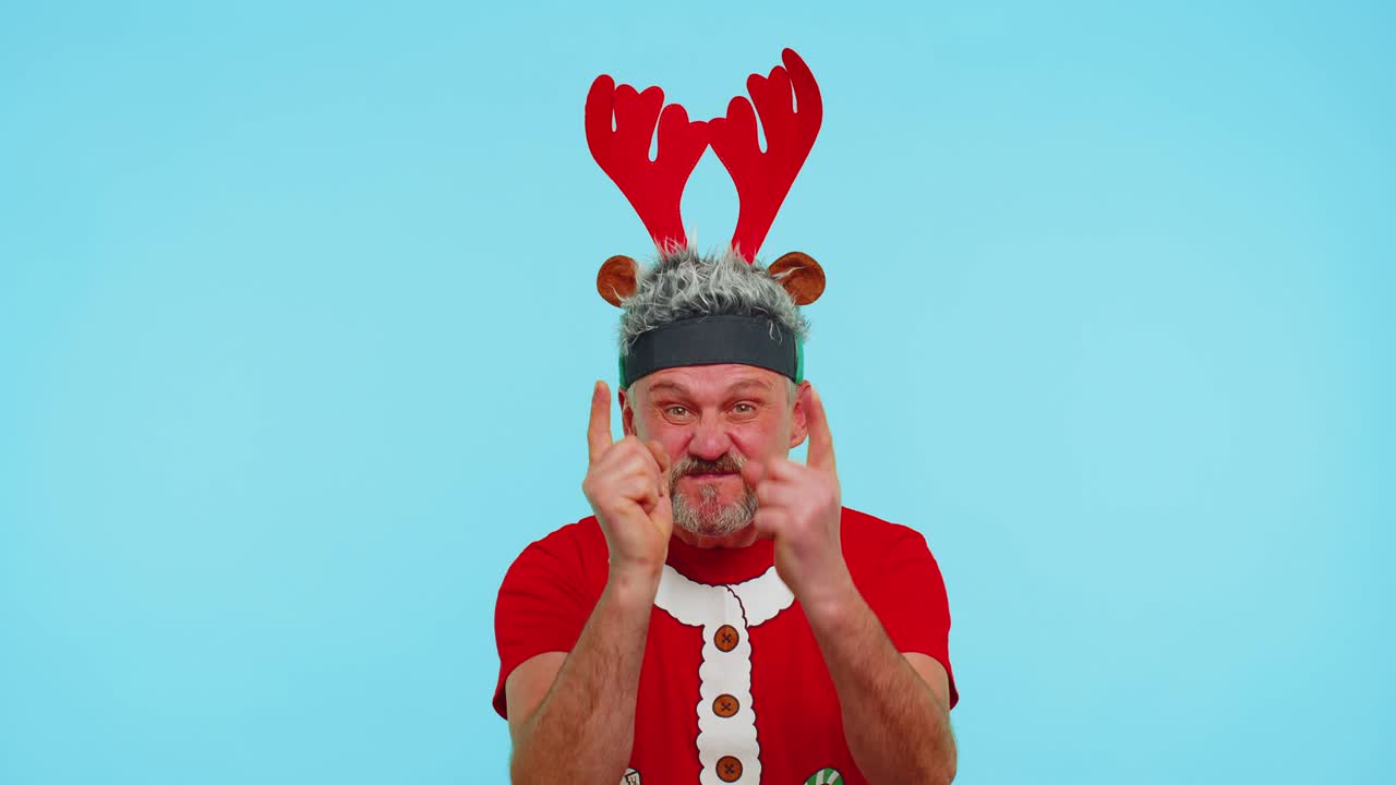 크리스마스 티셔츠를 입은 불만족한 남자가 불만족으로 손을 흔들며 실패에 대한 비난을 비난합니다.