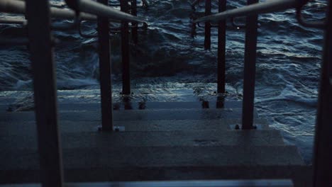 waves splashing against concrete steps leading to the rough ocean water