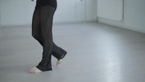 fit girl in black clothes performing contemporary. female dancer shows flowing motions, body and hands waves at white room. modern ballet dance choreography. young woman is moving smoothly