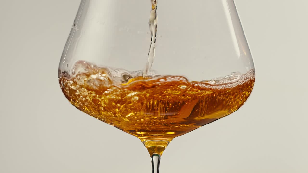 Orange or white wine bottle and glass against a sunset in a peaceful vineyard, pouring of ecological natural wine.