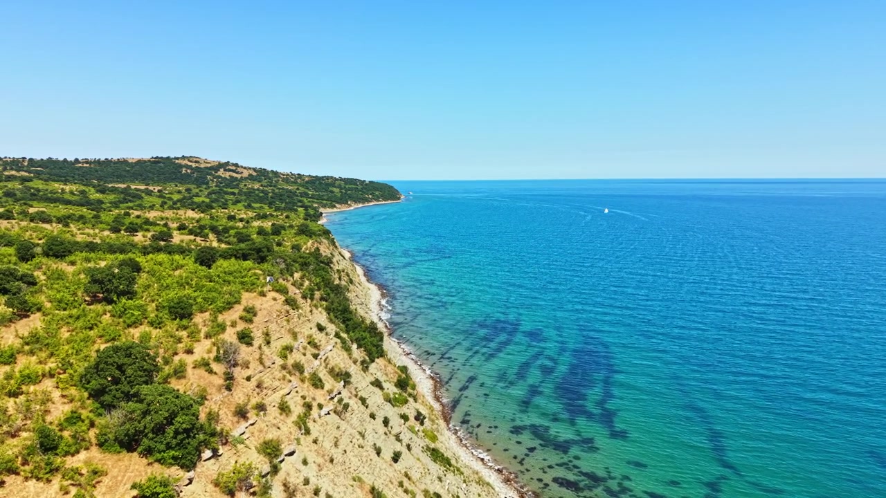 Panorama costiero con acqua cristallina e azzurra e colline verdi a mezzogiorno in una giornata di sole.