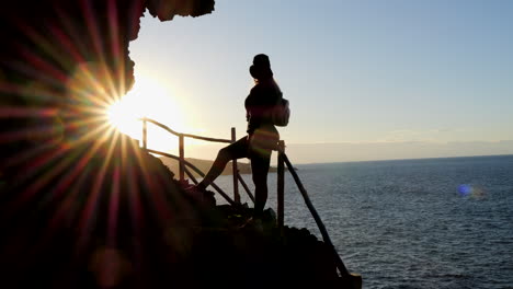 Fantástica-Toma-De-Una-Mujer-Joven-Con-Sombrero-Admira-Durante-La-Puesta-De-Sol,-El-Paisaje-Que-Se-Encuentra-En-La-Costa-Del-Municipio-De-Galdar-En-La-Isla-De-Gran-Canaria-Y-Durante-La-Puesta-De-Sol