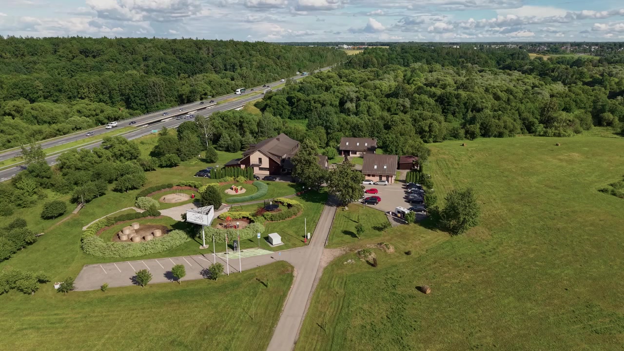 Kaunis dronevideo esittelee maaseututilaa, jossa on hoidettuja nurmikoita ja puutarhoja puurivien reunustaman valtatien vieressä. Eloisa kesäpäivänvalo, laajakulma ja terävä ilmakuva kuvattuna vaakasuunnassa.