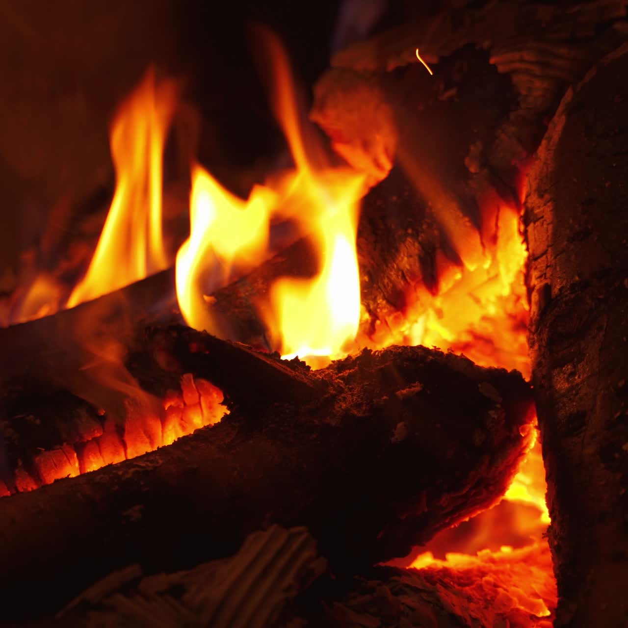 Romantic fireplace. Smoldering logs in hot flame burning in fireplace at home. Motion of fire in wood indoors. Close-up.