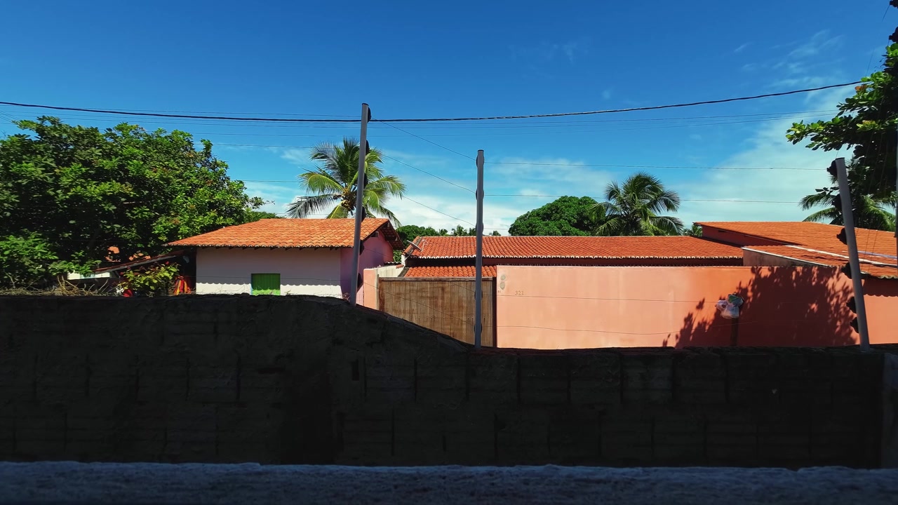 Time-lapse olhando pela janela de uma pequena casa de praia com outras casas de praia do outro lado da rua na pequena vila costeira de Sibaúma em Tibau do Sul, Brasil, no Rio Grande do Norte, perto de Pipa