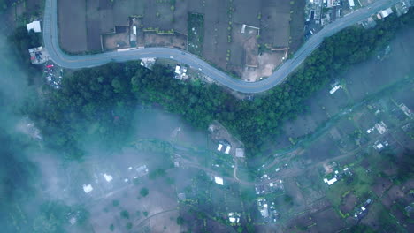 Top-down-static-aerial-footage-of-a-road-in-which-cars-are-driving-in-the-foggy-blue-light-of-the-sunrise-in-Guatemala