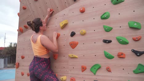 woman ascending a bouldering wall outdoors, cinematic shot