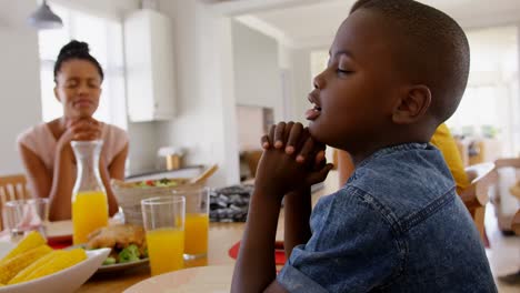 Seitenansicht-Einer-Schwarzen-Familie,-Die-Vor-Dem-Essen-Gemeinsam-Auf-Dem-Esstisch-In-Einem-Komfortablen-Zuhause-Betet,-4K