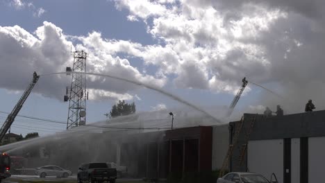 Feuerwehrleute-Besprühen-Gebäude-Mit-Wasser