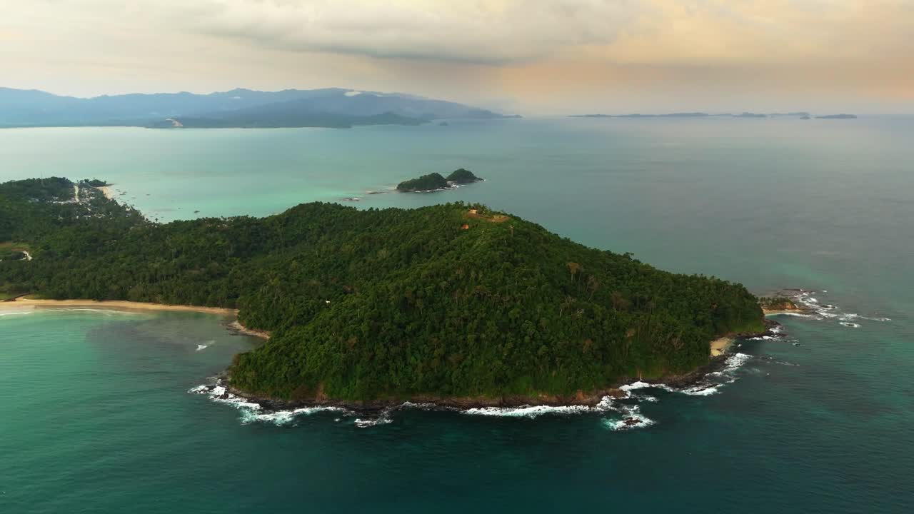 Dramatický letecký západ slunce nad zakřivenou zátokou a bujnými kopci ostrova San Vicente, Palawan, Filipíny