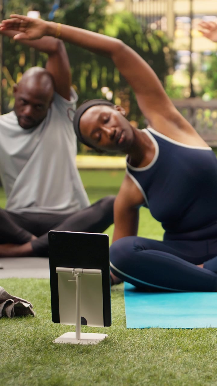 Vertical Video Young woman doing side stretch exercise in front of laptop with friends