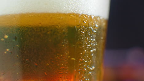 macro shot of a drop running over a glass of beer. sweat on a cold glass of beer. a dripping drop on a glass filled with beer.