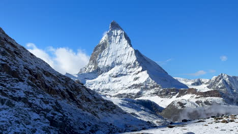 Lake-Riffelsee-Zermatt-Switzerland-Glacier-peak-Gornergrat-Railway-train-stop-October-clear-blue-sky-The-Matterhorn-peak-ski-resort-first-fresh-snowfall-landscape-scenery-autumn-Swiss-Alps-pan-down