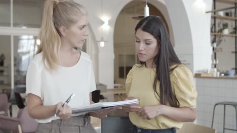 Serious-female-project-colleagues-discussing-document