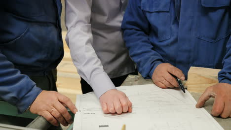 close-up view of male hands on blueprint in a factory