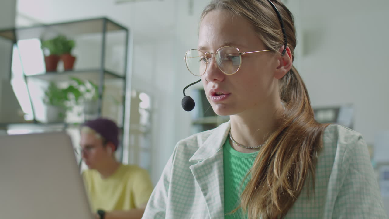 Ung forretningskvinne med headset snakker via nettsamtale på bærbar PC