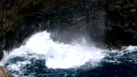 big waves crashing on cliff of lava rocks.