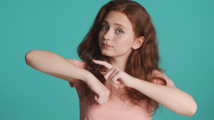 Redheaded girl in front of camera on turquoise background.