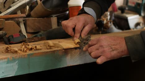 carpenter using a spokeshave to create a smooth bevel on a wooden plank