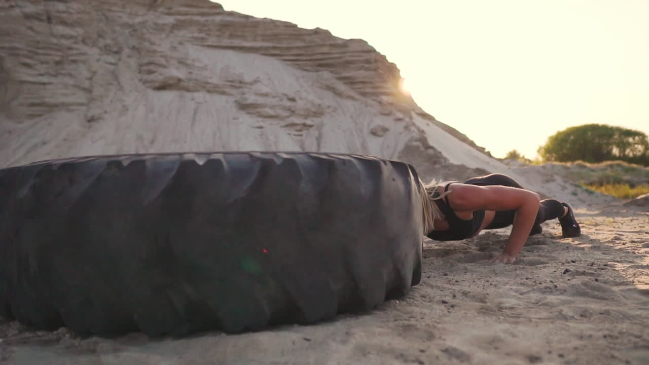 entrenadoras de chicas al aire libre saltando burpee a través de la rueda. entrenamiento crossfit entrenamiento. puesta de sol