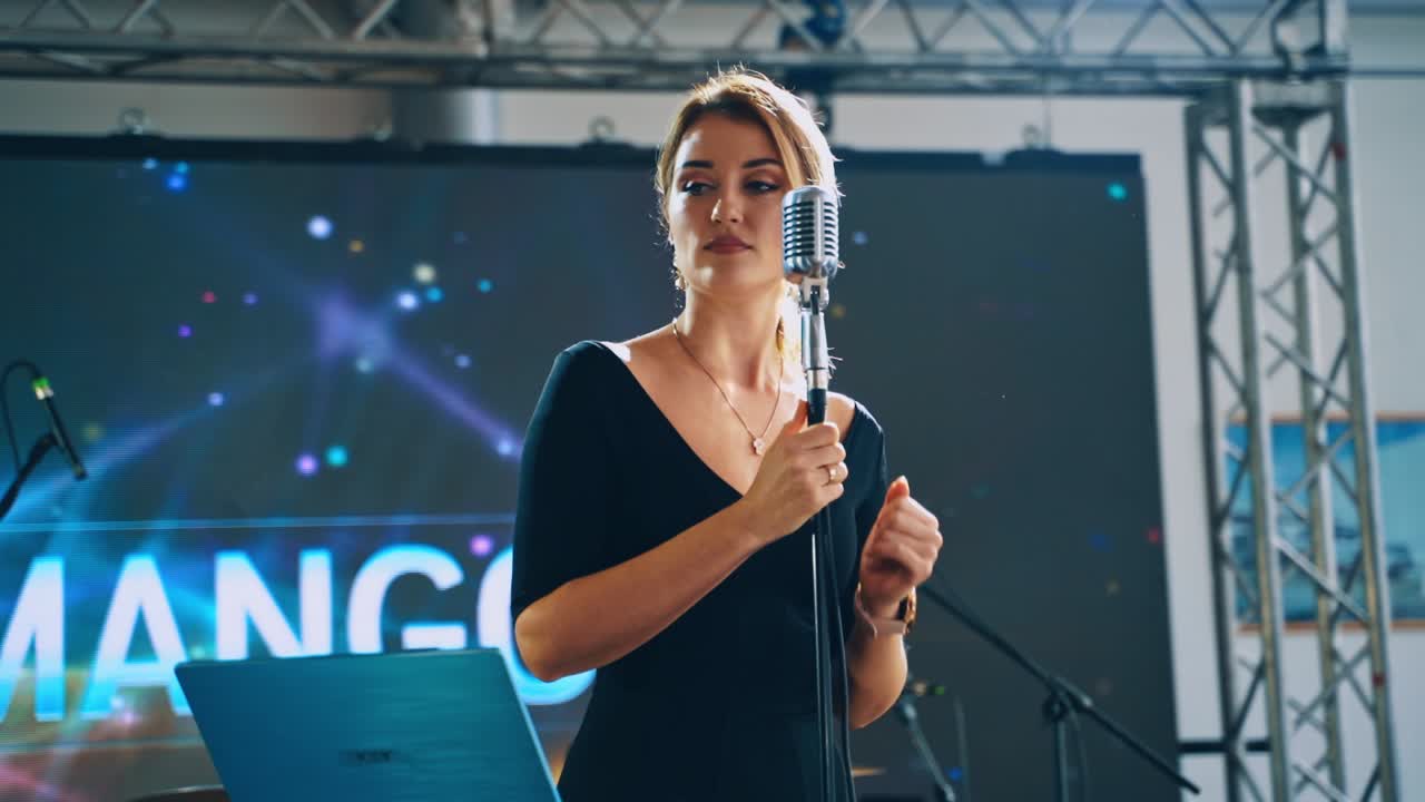 Female singer performs music into the microphone. Professional vocalist singing on the stage in the music hall.