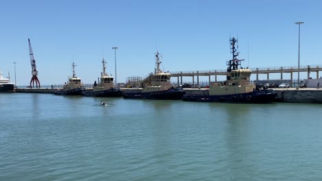 some armed forces ships on the river with some sportsmen doing canoeing, alcântara, portugal