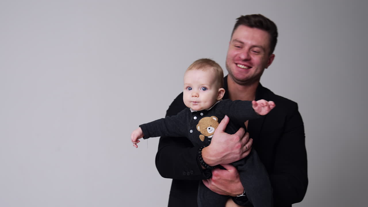 Loving father holding a child and kissing him. Happy dad and son concept. White backdrop.