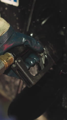 hand of professional worker in uniform inserting fuel gun to fill vehicle with fuel. driver prepares heavy mining transportation for work closeup