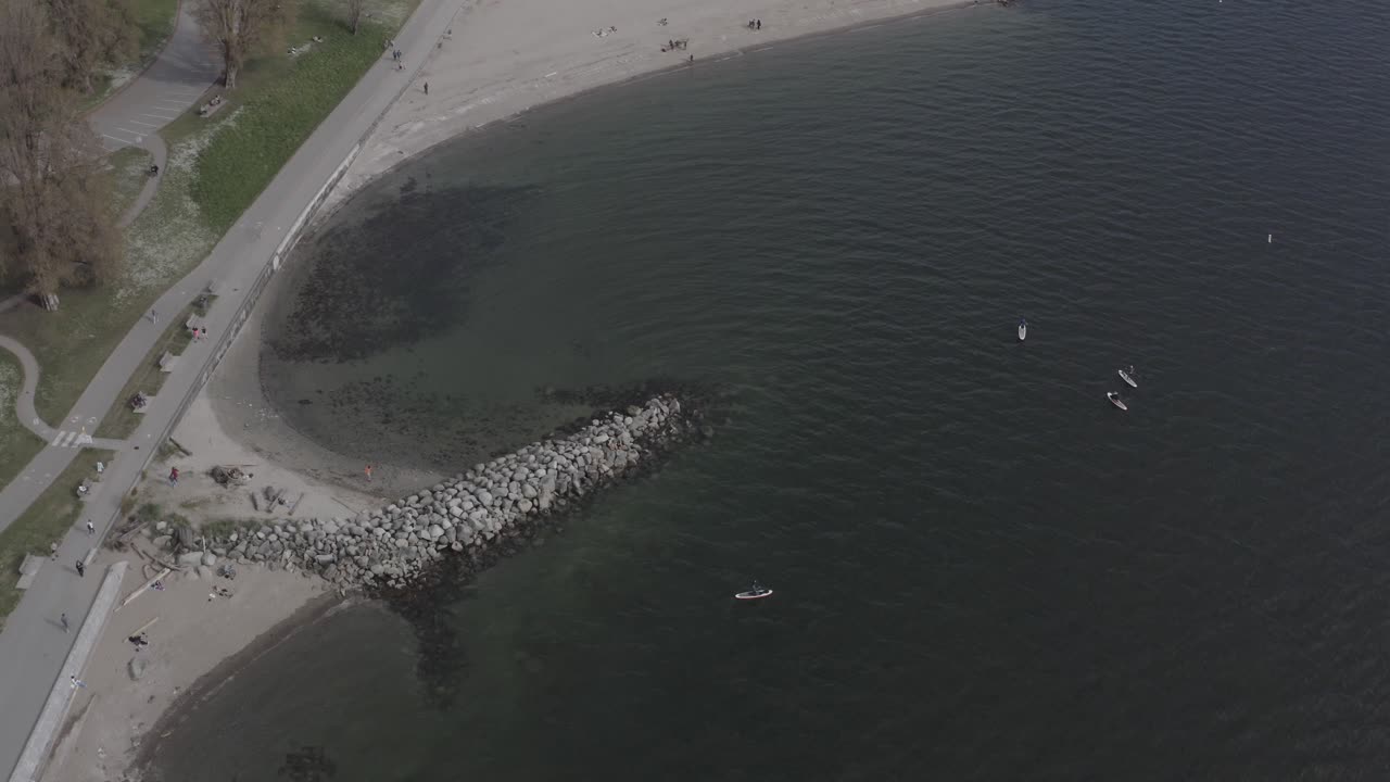 사람들이 방파제에서 운동하는 동안 재미있는 여름 체력 경험을 즐기는 패들 보드 서퍼들의 영국식 만 선셋 비치 조감도