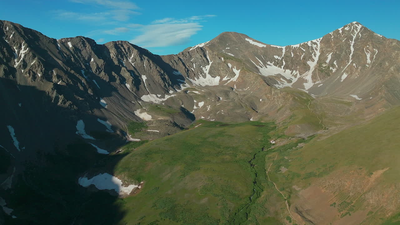 drone cinematográfico aéreo de manhã cedo nascer do sol trilha de caminhada cinzas e torres 14er picos montanhas rochosas colorado paisagem deslumbrante vista meio do verão verde bela neve no topo para trás para cima alto movimento