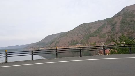 a serene drive along lake kawaguchi with mountain views, captured in soft daylight, showcasing the tranquil beauty of fujikawaguchiko
