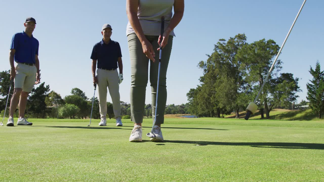 밝은  ⁇ 은 날에 골프 코스에서 골프 공을 구 ⁇ 에서 제거하는 백인 고위 여성