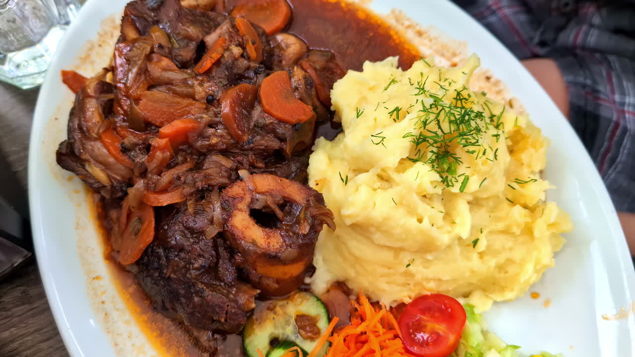 고기 오소부코 (beef ossobucco) 는 폴렌타 (polenta) 와 채소와 함께 제공된다.