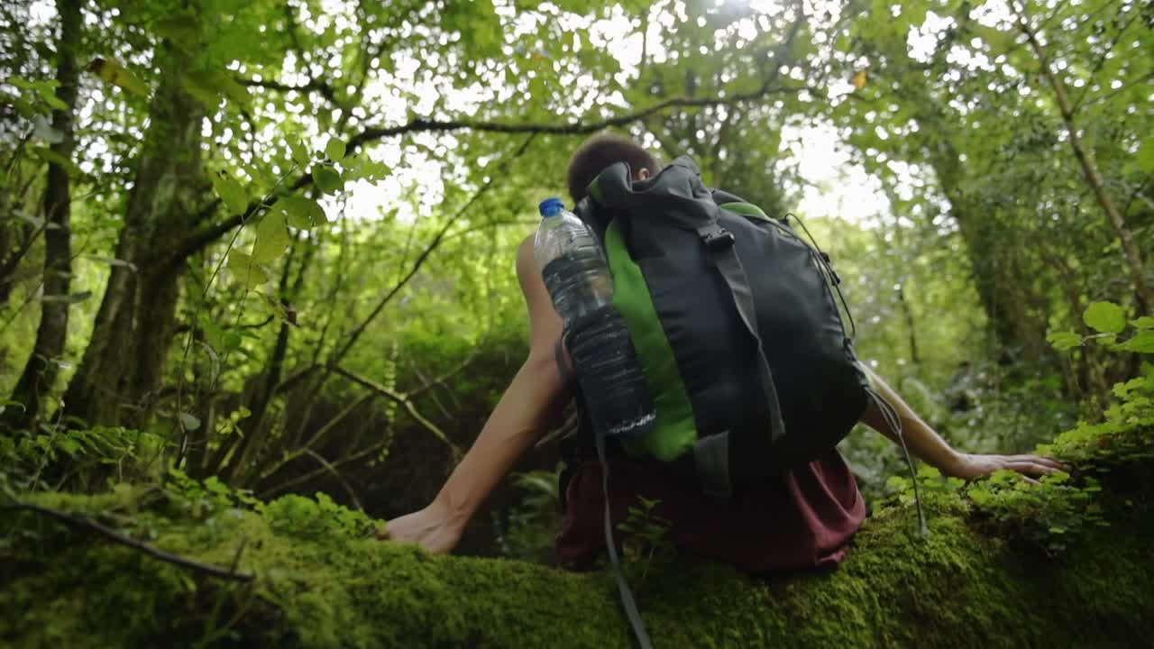 Tourist with backpack walking up on hill