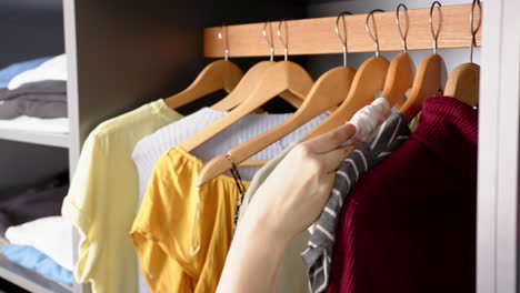 selecting clothes from wardrobe, person organizing colorful outfits on hangers