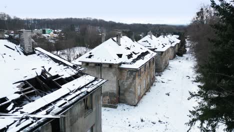 Luftaufnahme-Einer-Reihe-Verlassener,-Heruntergekommener-Gebäude-In-Einer-Verschneiten-Landschaft,-Die-Eine-Unheimliche-Und-Trostlose-Atmosphäre-Schafft