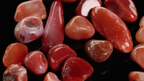 red jasper stones slowly rotate against a black background, highlighting their smooth textures and vibrant colors