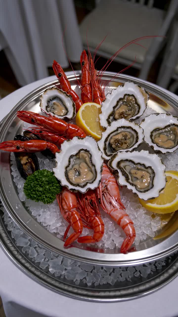 Top-down view of a seafood platter with oysters and shrimp on ice, garnished with lemon and parsley