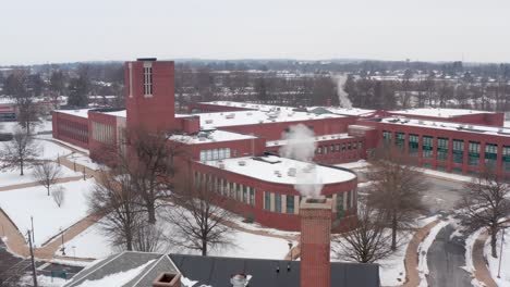 aerial reveal of large school, college, university building during winter snow