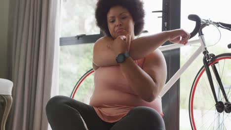 video of midsection of plus size african american woman in sport clothes stretching at home