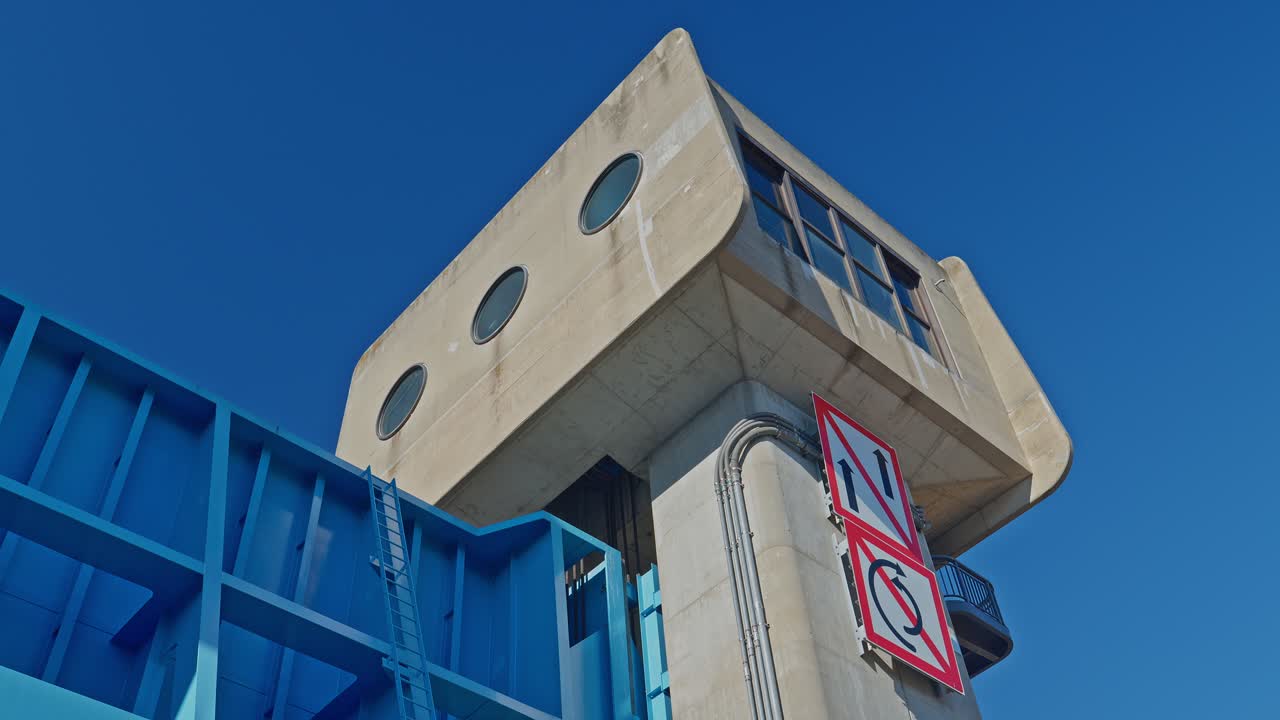 Detailed bottom-up shot of blue steel gates and concrete towers. Highlights the massive scale and industrial textures of Tokyo's iconic water gate
