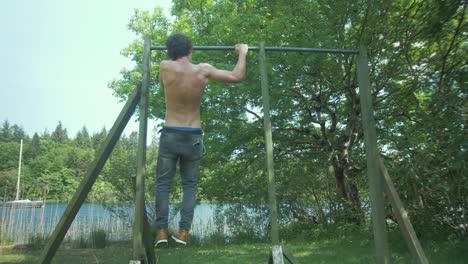 airwalk pull-ups performed by a fit topless young man