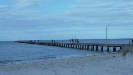 foto de playa de agua del muelle y gente caminando fondo de barco alto anochecer centeno