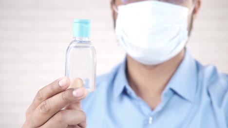 person holding hand sanitizer bottle with mask