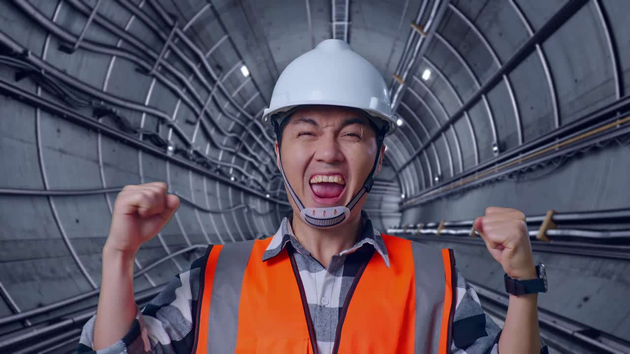 Close Up Of Asian Male Engineer With Safety Helmet Screaming Goal Celebrating Working In Underground Subway Tunnel