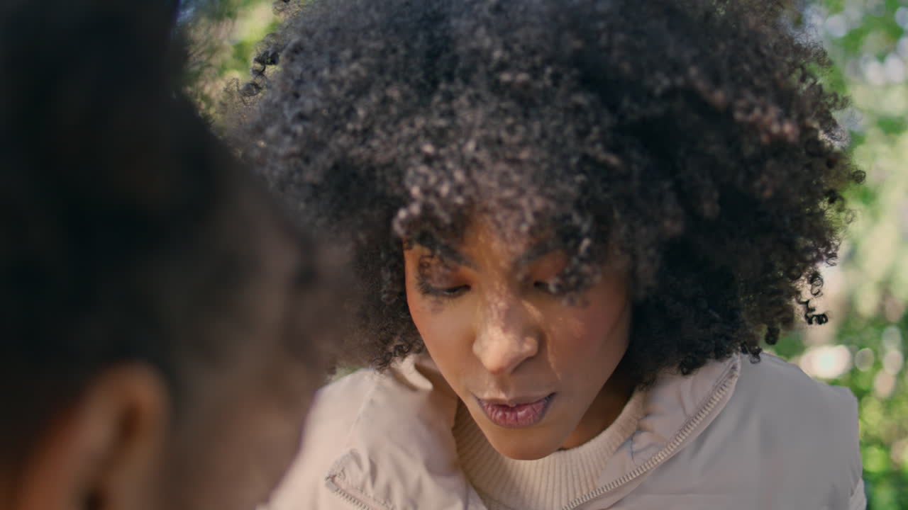 una mujer sonriente sentada con su hija en el jardín de cerca.