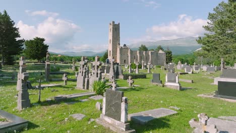 smooth dolly shot flying over a graveyard approaching a medieval stone church on a sunny day